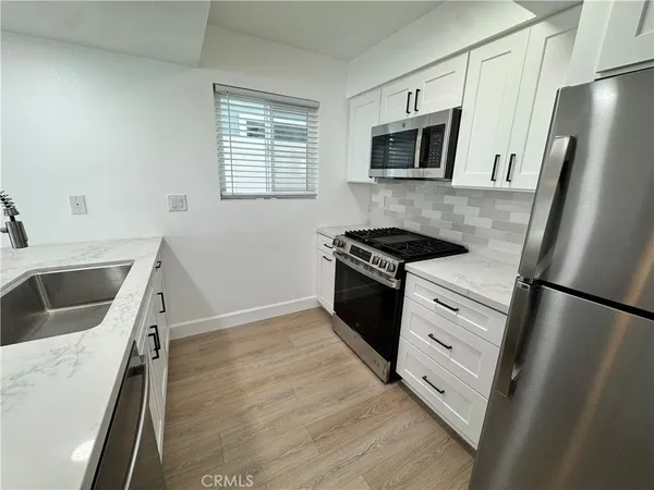 a kitchen with granite countertop a refrigerator stove and sink