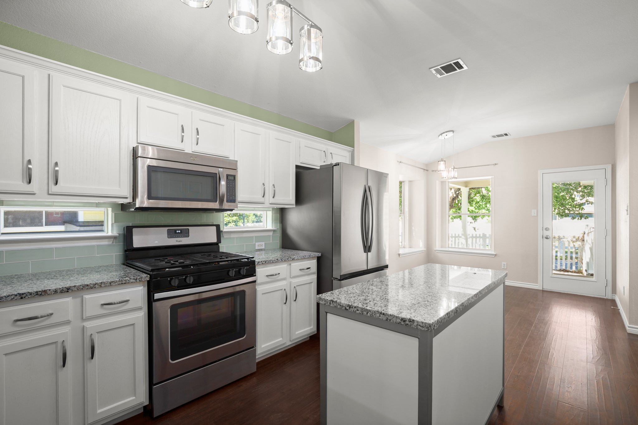 151 Sampson Kyle, TX 78640 - Photo 6 of 23 The kitchen balances functionality and personality with granite countertops, generous prep space, gas cooking, stainless appliances, and a striking green glass subway tile backsplash.