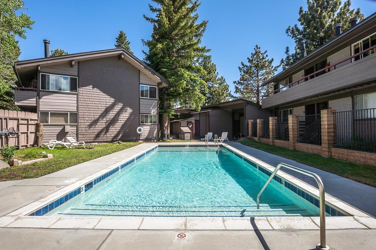 165 Old Mammoth Road, Unit 3 Mammoth Lakes, CA 93546 - Photo 46 of 48 Outdoor swimming pool with concrete decking, surrounded by mature conifer trees and two-story buildings featuring horizontal siding and shake siding