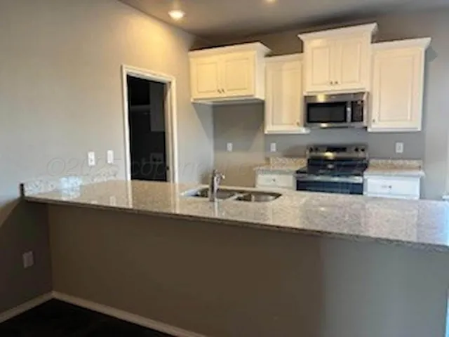 a kitchen with kitchen island a stove a sink and white cabinets