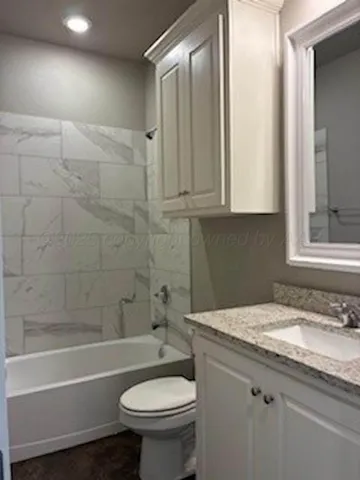 a bathroom with a granite countertop sink a toilet and shower