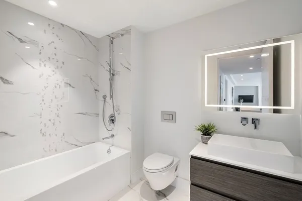 a bathroom with a sink a toilet a mirror a bathtub and shower