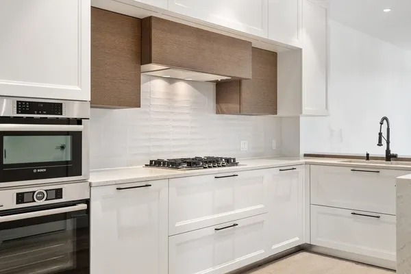 a kitchen with white cabinets and appliances