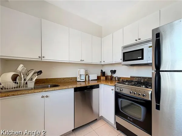 a kitchen with granite countertop white cabinets and stainless steel appliances