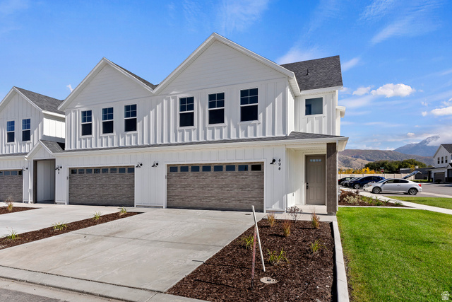 Modern farmhouse style home with board and batten siding, driveway, and roof with shingles