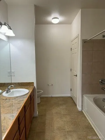 a bathroom with a granite countertop sink and a bathtub
