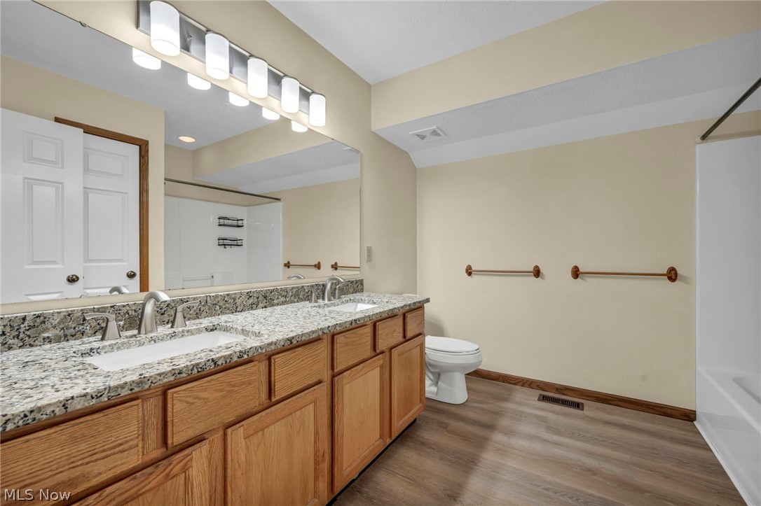 9842 Johnnycake Ridge Road Mentor, OH 44060 - Photo 25 of 40 Bathroom featuring a double vanity with granite-finish countertops and integrated sinks, wood-finish cabinetry, and brushed nickel faucets