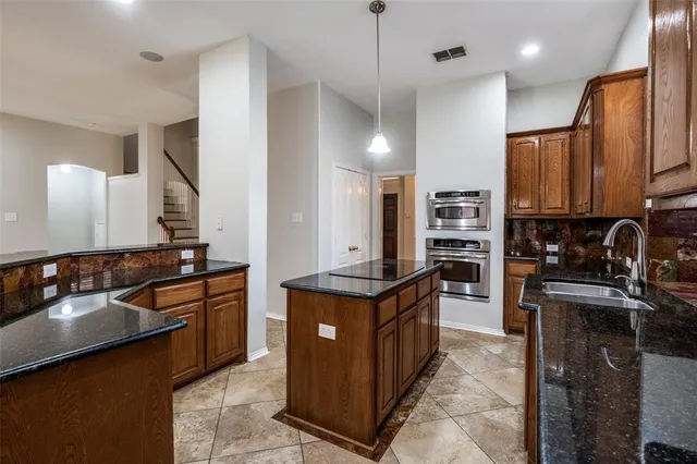 a kitchen with kitchen island granite countertop a sink stove and refrigerator