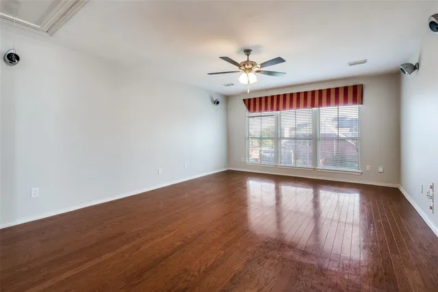 an empty room with wooden floor fan and windows
