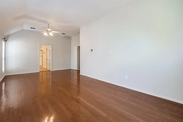a view of empty room with wooden floor and ceiling fan