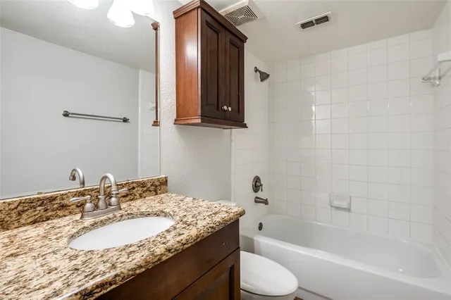 a bathroom with a granite countertop sink toilet and bathtub