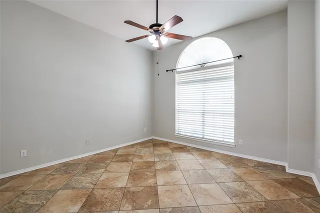 an empty room with chandelier fan and windows