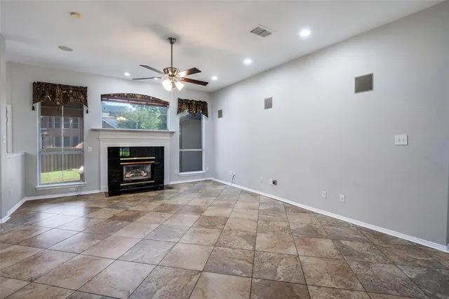 an empty room with fireplace and a chandelier fan