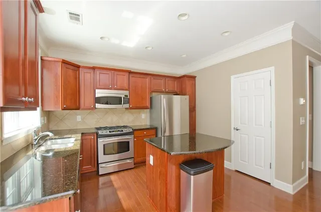 a kitchen with stainless steel appliances granite countertop a refrigerator a sink dishwasher a stove and white countertops with wooden floor