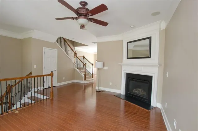 a view of a livingroom with a fireplace a ceiling fan and wooden floor
