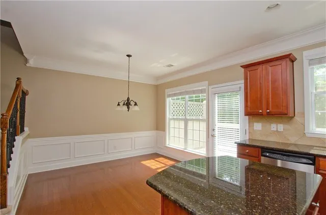 a kitchen with stainless steel appliances kitchen island granite countertop a refrigerator a stove and a wooden floors
