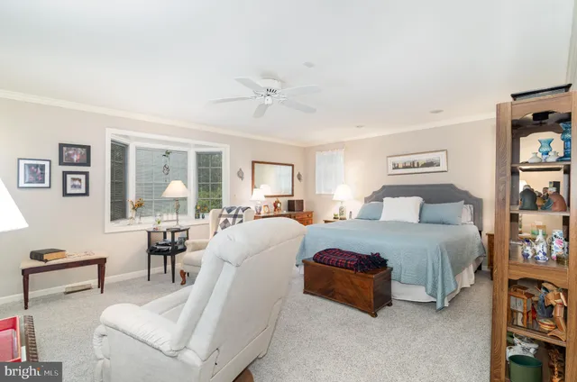 a spacious bedroom with a bed a table and bookshelf