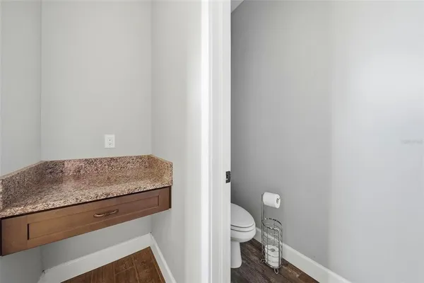 a view of a hallway with wooden floor and a bathroom