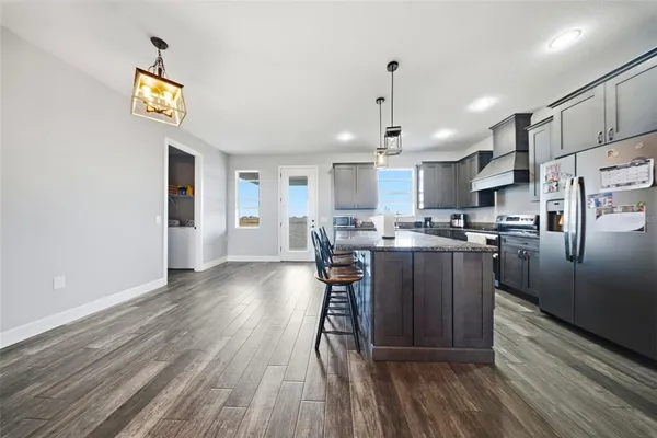 a kitchen with stainless steel appliances granite countertop a refrigerator a sink a stove and a wooden floors