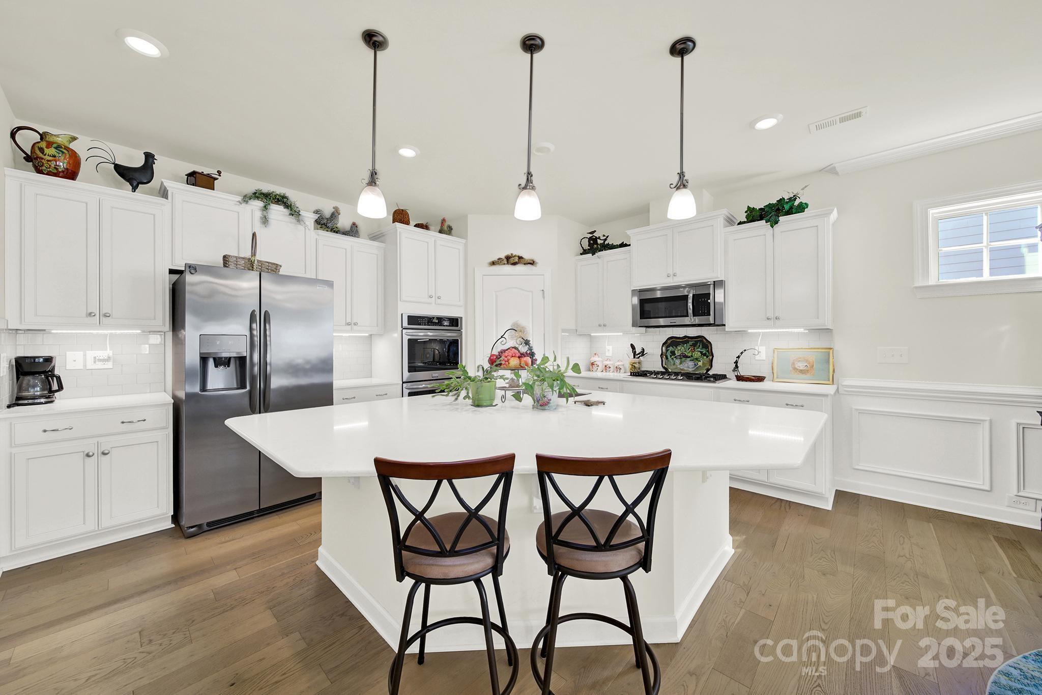 3097 Arches Bluff Circle Lancaster, SC 29720 - Photo 9 of 40 a kitchen with stainless steel appliances kitchen island granite countertop a table chairs and a refrigerator