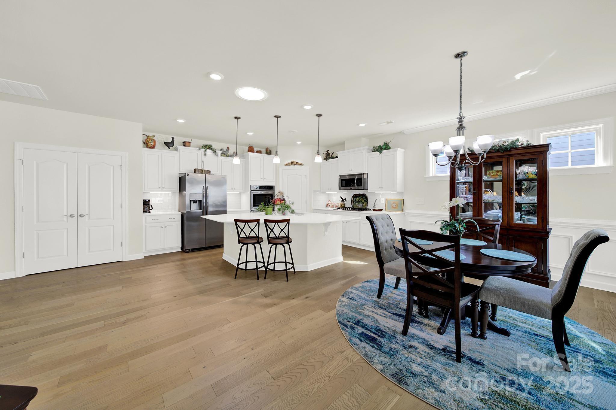 3097 Arches Bluff Circle Lancaster, SC 29720 - Photo 10 of 40 a kitchen with stainless steel appliances kitchen island granite countertop a dining table chairs and white cabinets