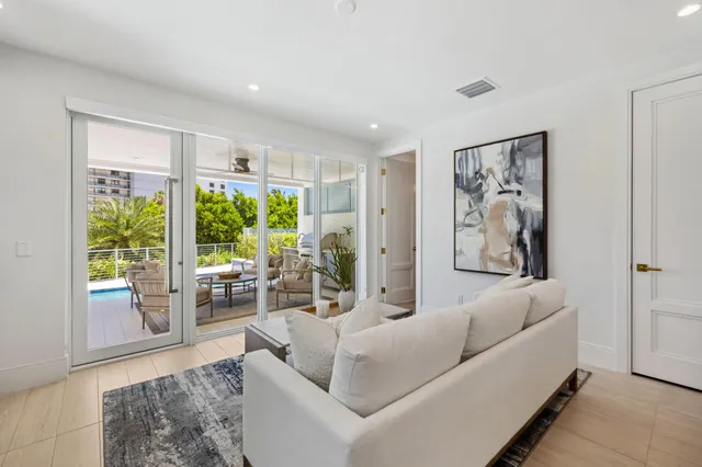 a large white kitchen with stainless steel appliances granite countertop a stove a sink a refrigerator and white cabinets with wooden floor