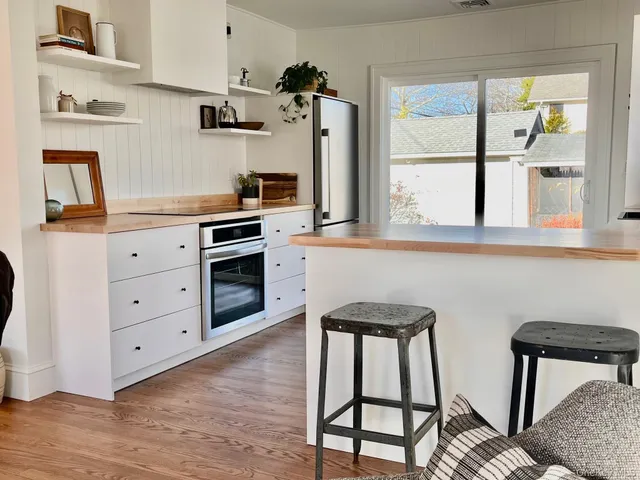 a kitchen with stainless steel appliances kitchen island a table chairs in it and wooden floors