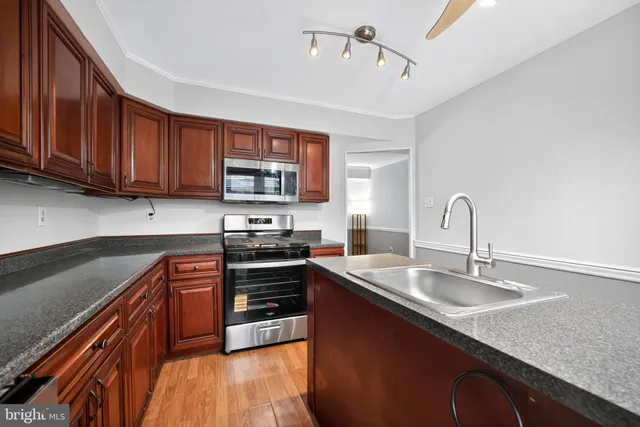 a kitchen with stainless steel appliances granite countertop a sink stove and cabinets