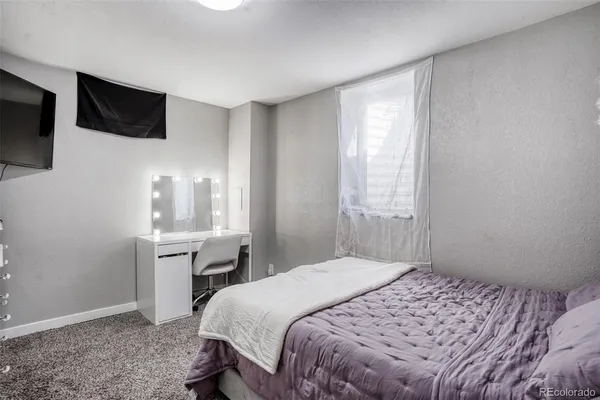 a bedroom with a bed a flat screen tv and a window