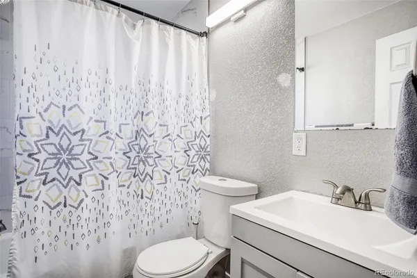 a bathroom with a sink a toilet and a shower curtain