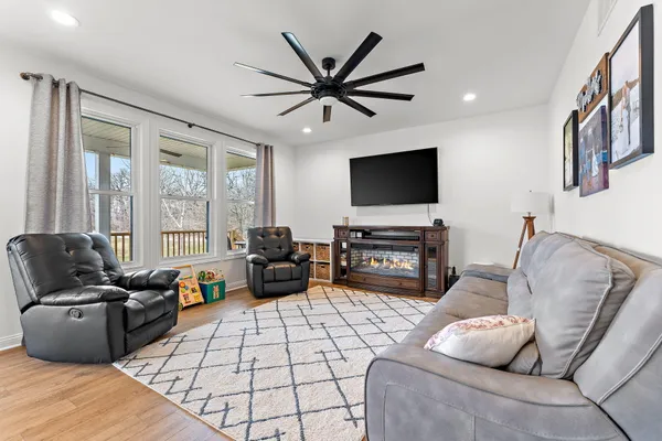 a living room with furniture a flat screen tv and a floor to ceiling window