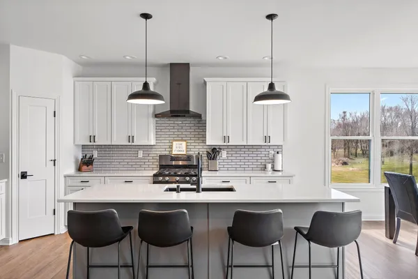 a kitchen with stainless steel appliances granite countertop a sink a stove a window and chairs