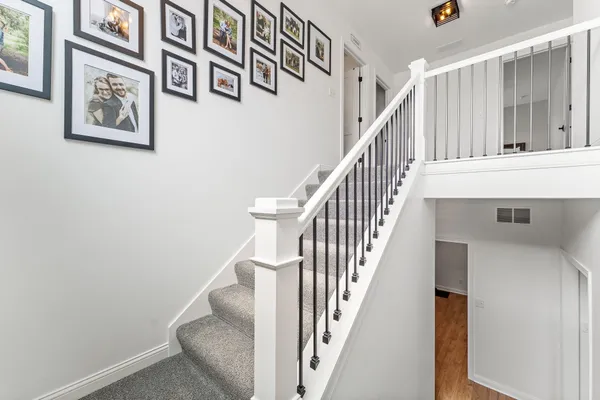 a view of staircase with lots of frames on wall and a painting on the wall