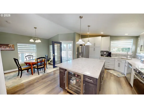 a open kitchen with stainless steel appliances kitchen island granite countertop a table chairs and a refrigerator