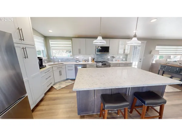 a kitchen with stainless steel appliances granite countertop a table chairs and a refrigerator