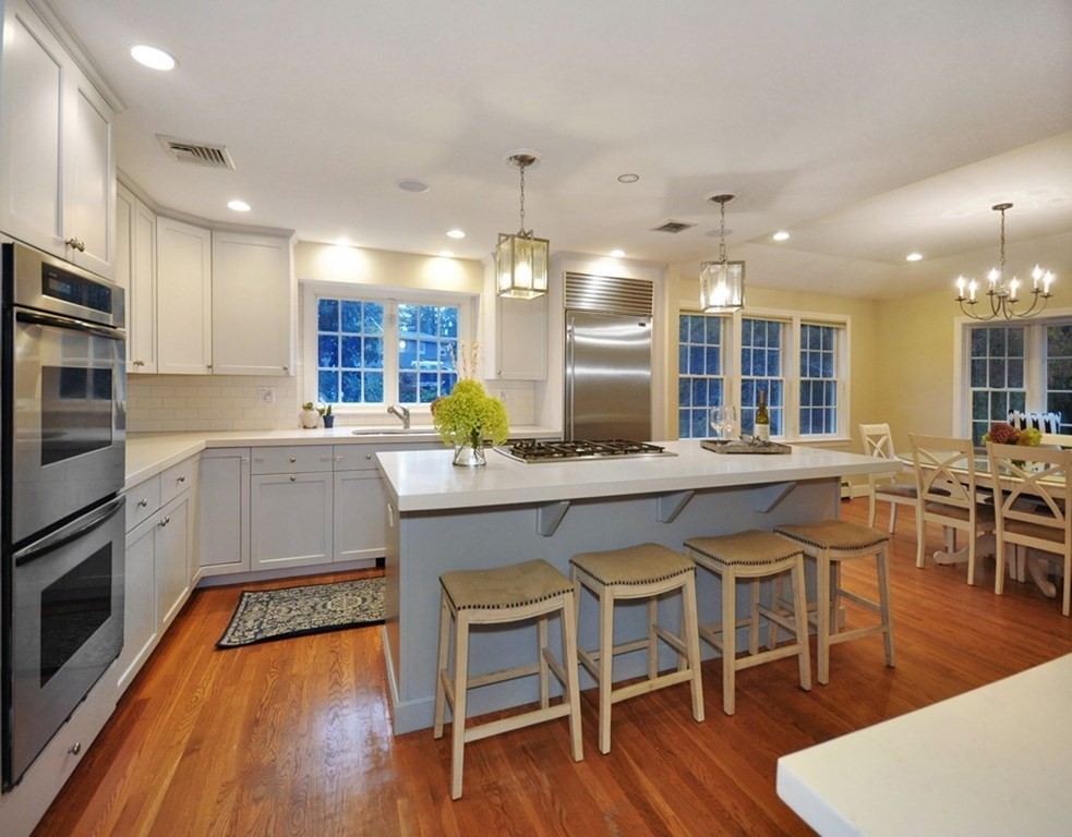 110 Warren Road Sudbury, MA 01776 - Photo 4 of 38 a kitchen with stainless steel appliances granite countertop a stove top oven a sink a dining table and chairs with wooden floor