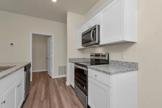 a kitchen with white cabinets stainless steel appliances and a sink
