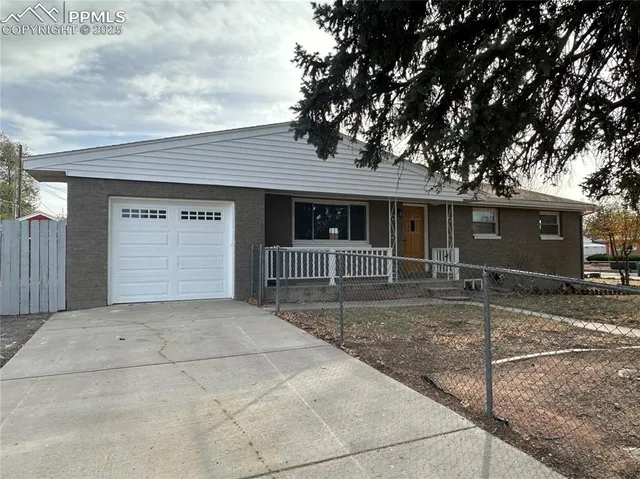 a view of a house with a large tree and wooden fence