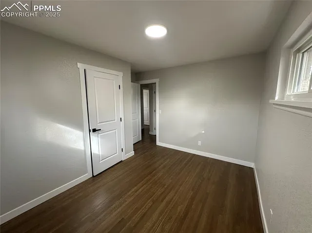 an empty room with wooden floor and window