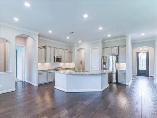 a large kitchen with stainless steel appliances granite countertop a stove and a wooden floors