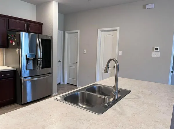 a kitchen with stainless steel appliances granite countertop a refrigerator a stove and a sink with wooden countertops
