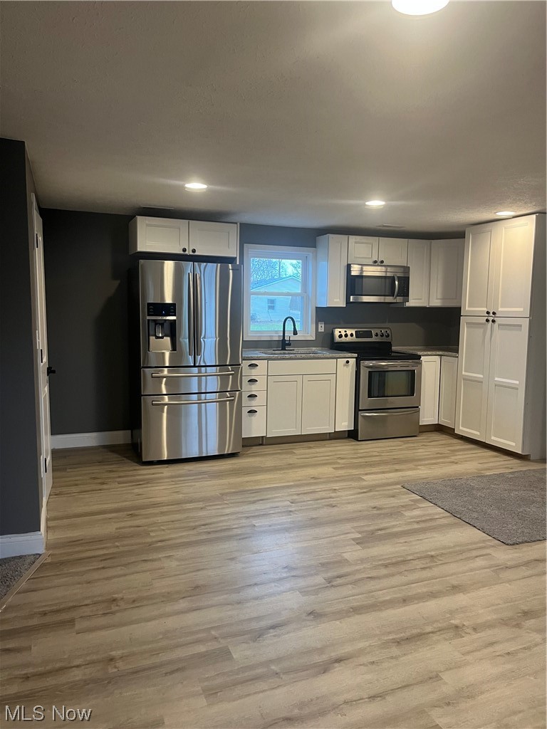 419 Stable Road Lagrange, OH 44050 - Photo 2 of 21 Kitchen with sink, light hardwood / wood-style floors, range, white cabinets, and fridge