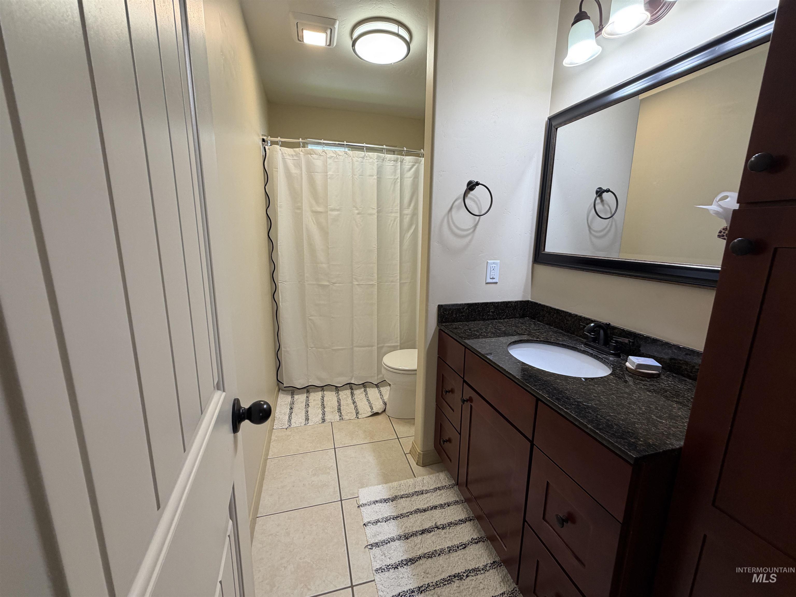 2000 M Street Heyburn, ID 83336 - Photo 9 of 15 Bathroom featuring a dark wood-finish vanity with a dark speckled countertop and an undermount sink