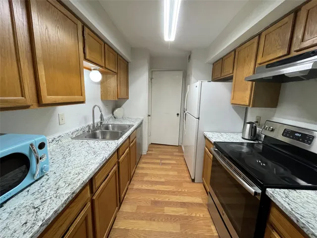 a kitchen with granite countertop stainless steel appliances a sink stove top oven and cabinets