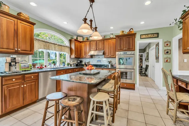 a kitchen with stainless steel appliances granite countertop a stove top oven a sink a dining table and chairs with wooden floor