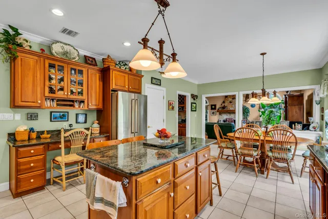 a open kitchen with stainless steel appliances granite countertop a stove top oven a dining table and chairs with the wooden floor