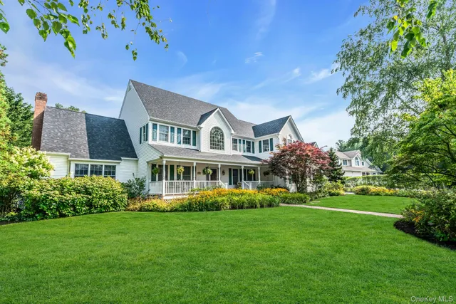 a front view of a house with garden and trees