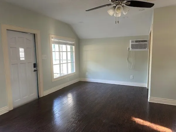 an empty room with wooden floor chandelier fan and windows