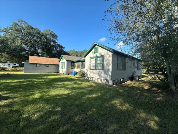 a view of a house with a big yard and large tree