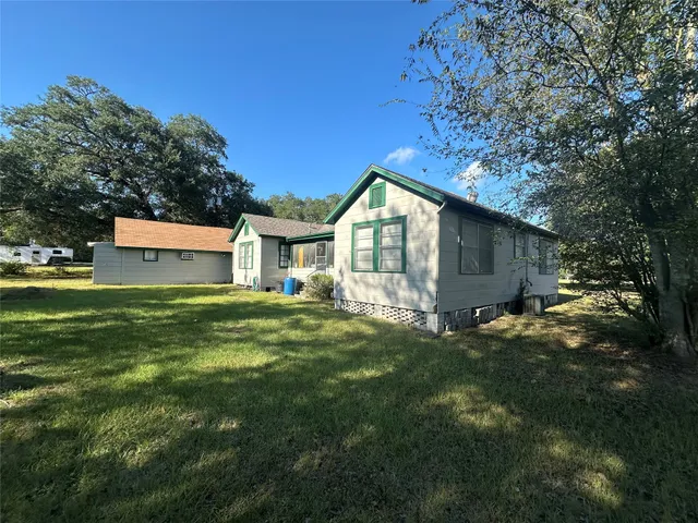 a view of a house with a big yard and large tree